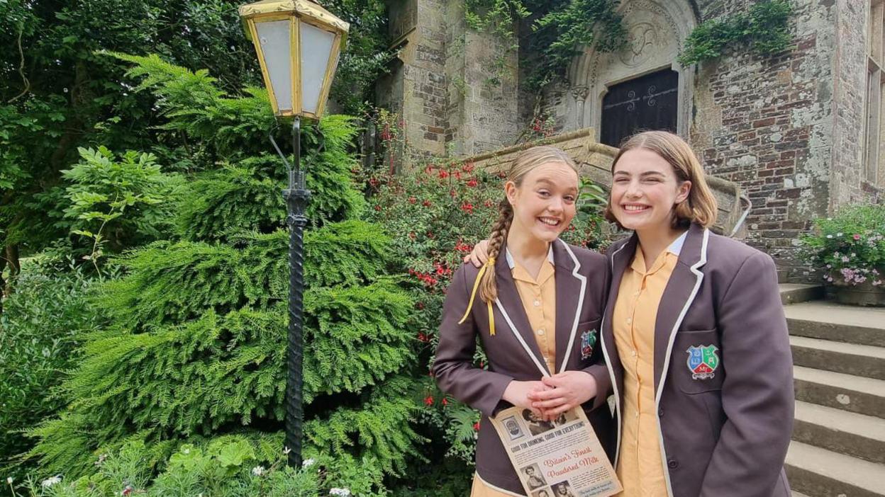 Danya Griver and Ella Bright smiling at the camera outside Hartland Abbey