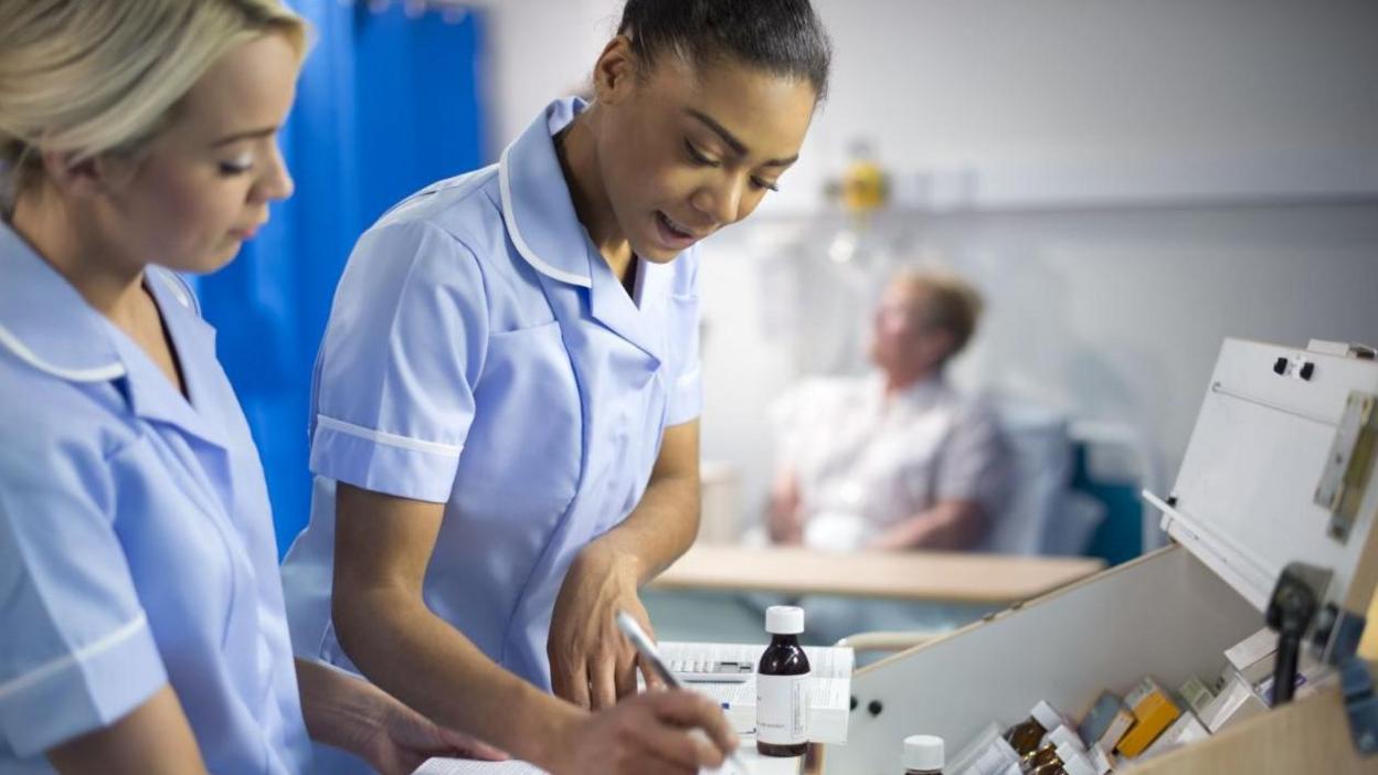 Nurses dispensing medicine on hospital ward.