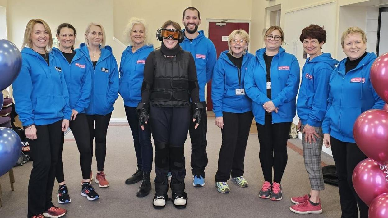 New recruits stand with someone wearing the GERT suit 