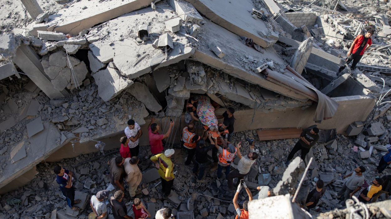 People remove a covered body from the rubble of a missile-hit house in Khan Younis on 2 October.