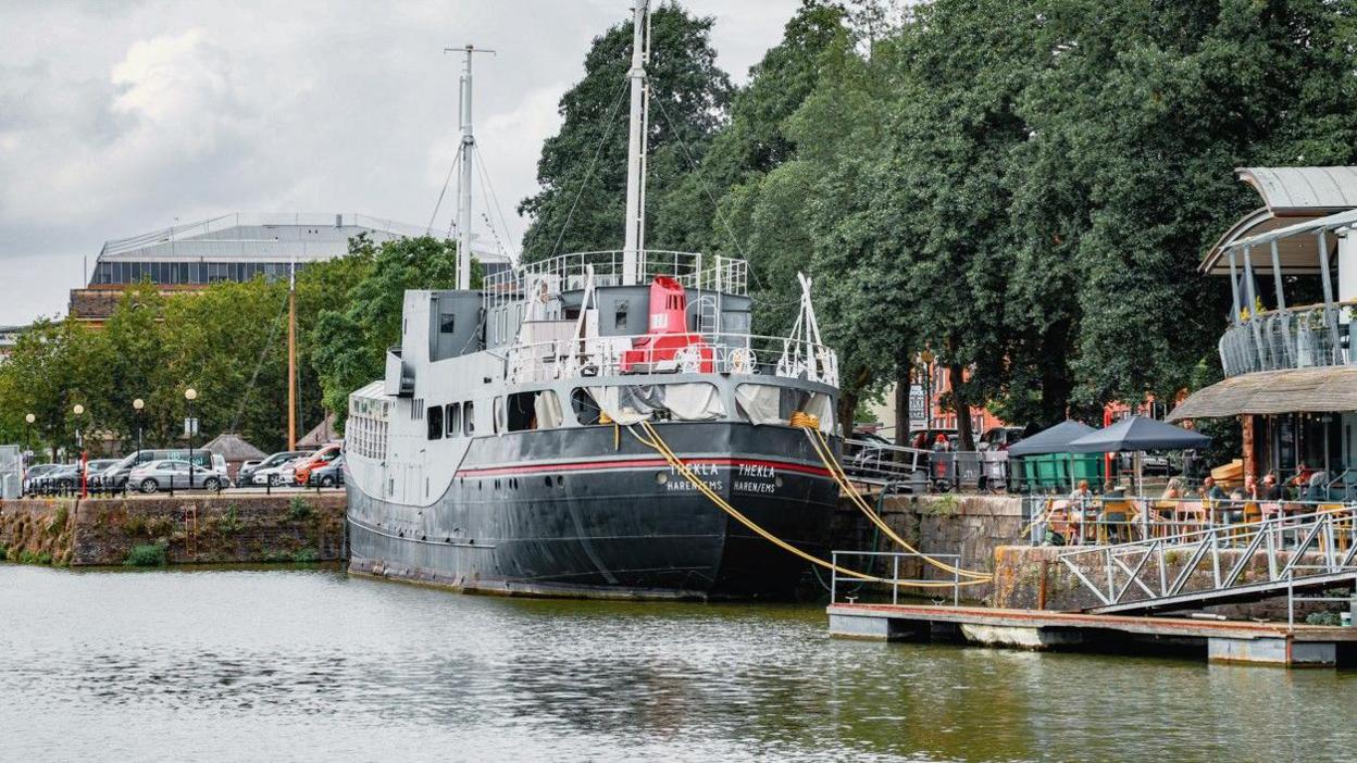 A view from the water of the bow of the Thekla Boat, painted in black, red and grey colours 