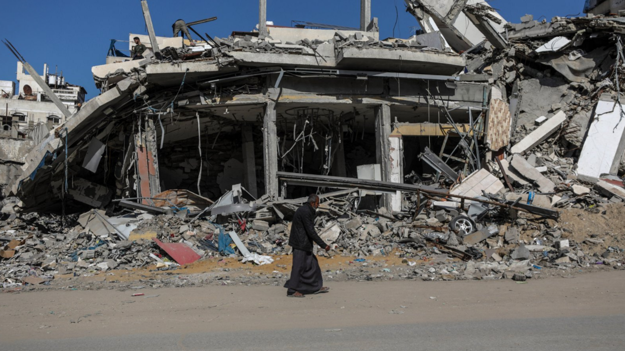 An elderly Palestinian man walks past a destroyed building in Gaza City