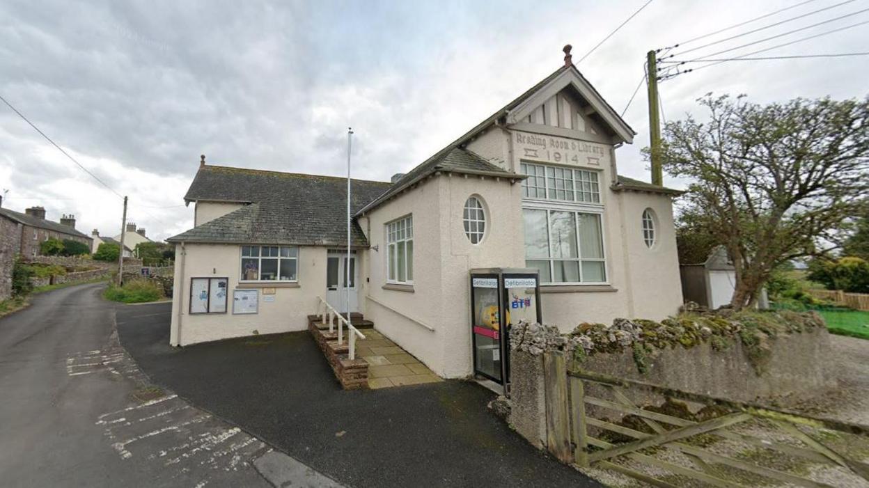 Sockbridge and Tirril Town Hall. The building is white with a slate roof. A sign above the main windows says, Reading Room and Library 1914.