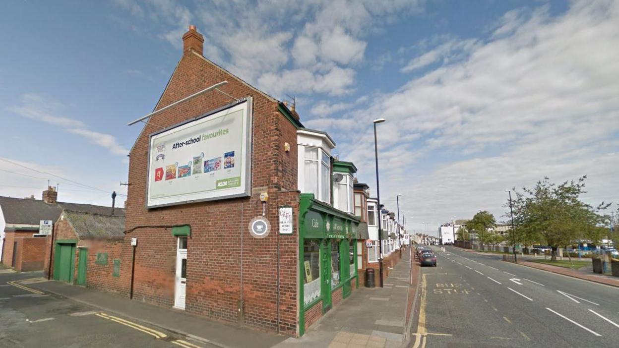 A six metre by three metre advertising board on the gable end of a two-storey property, the ground floor of which is a green-fronted café. 