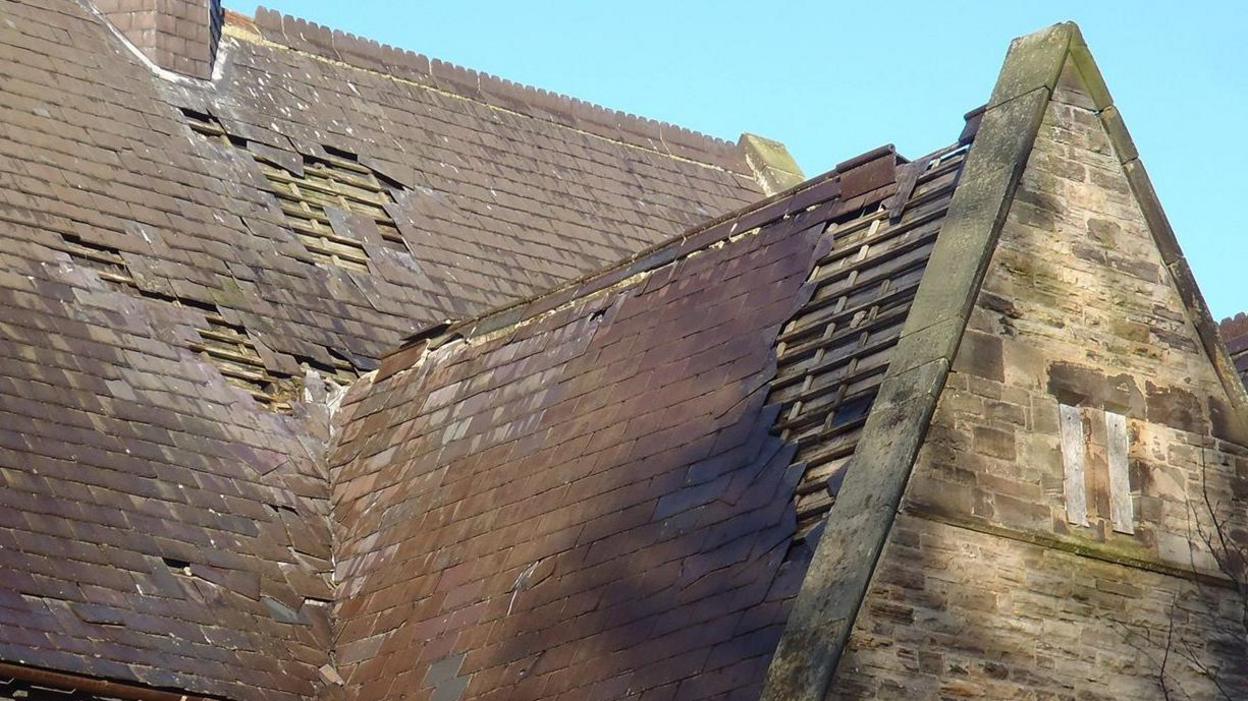 A close-up shot of the church's roof which has several tiles missing, exposing the wooden slats underneath.