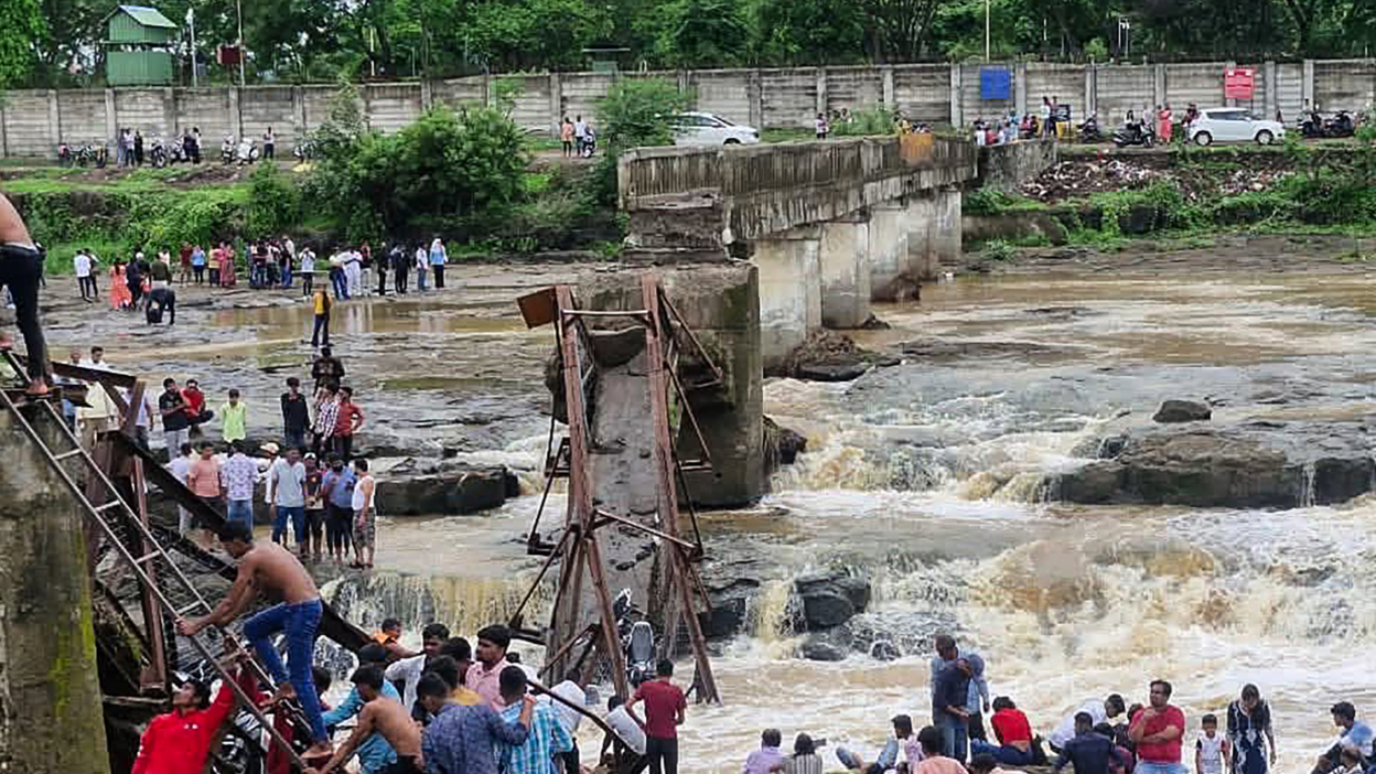 People gather near the site of a bridge collapse at Indrayani river near Kundamala village