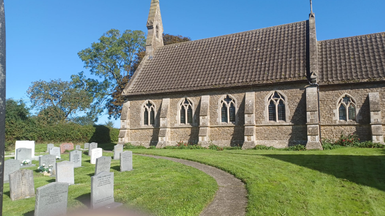 The exterior of a church with some tombstones in the foreground