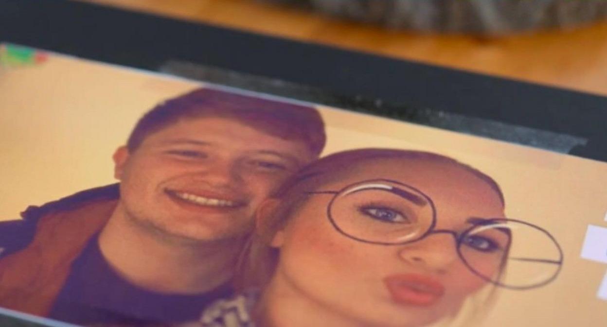 A page from Cameron's scrapbook has a photo of the couple taped to a black page. The two are younger, Cameron in a black and orange jacket behind Weronika in a striped top and with a funny filter that gives her big glasses and freckles