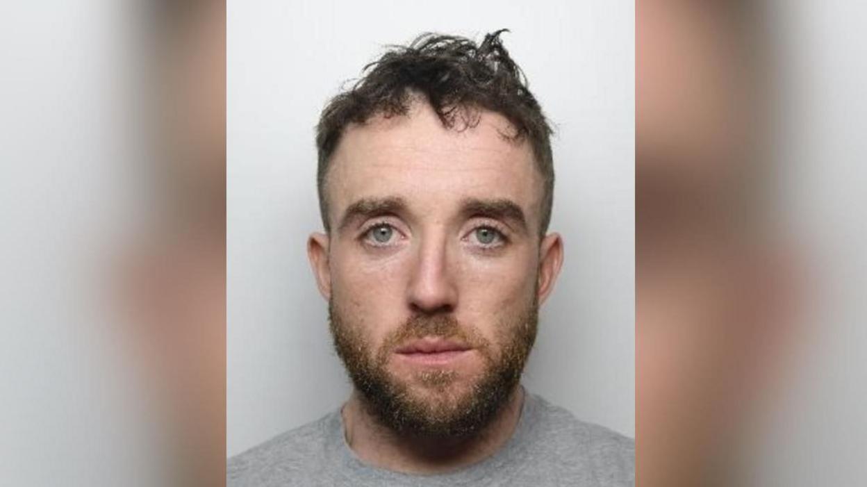 Police mugshot of Francis O'Connor. He has short dark hair, shaved on the sides, with a short beard. 