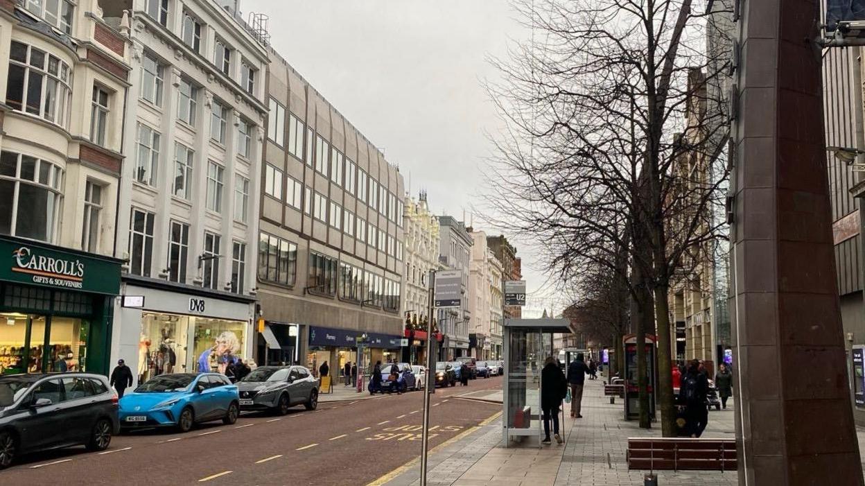 A generic shot of Belfast city centre, royal avenue area... Rows of shops with cars parked on pavements