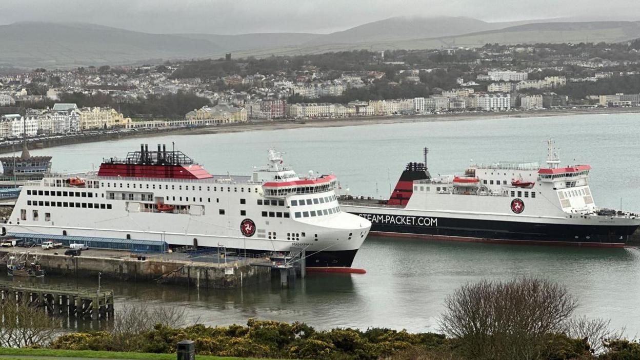 The Manxman and Ben-my-Chree ferries moored in Douglas Harbour. The are painted in the Isle of Man Steam Packet Company's colours of white, red and black. Douglas Bay and Promenade can be seen the background.