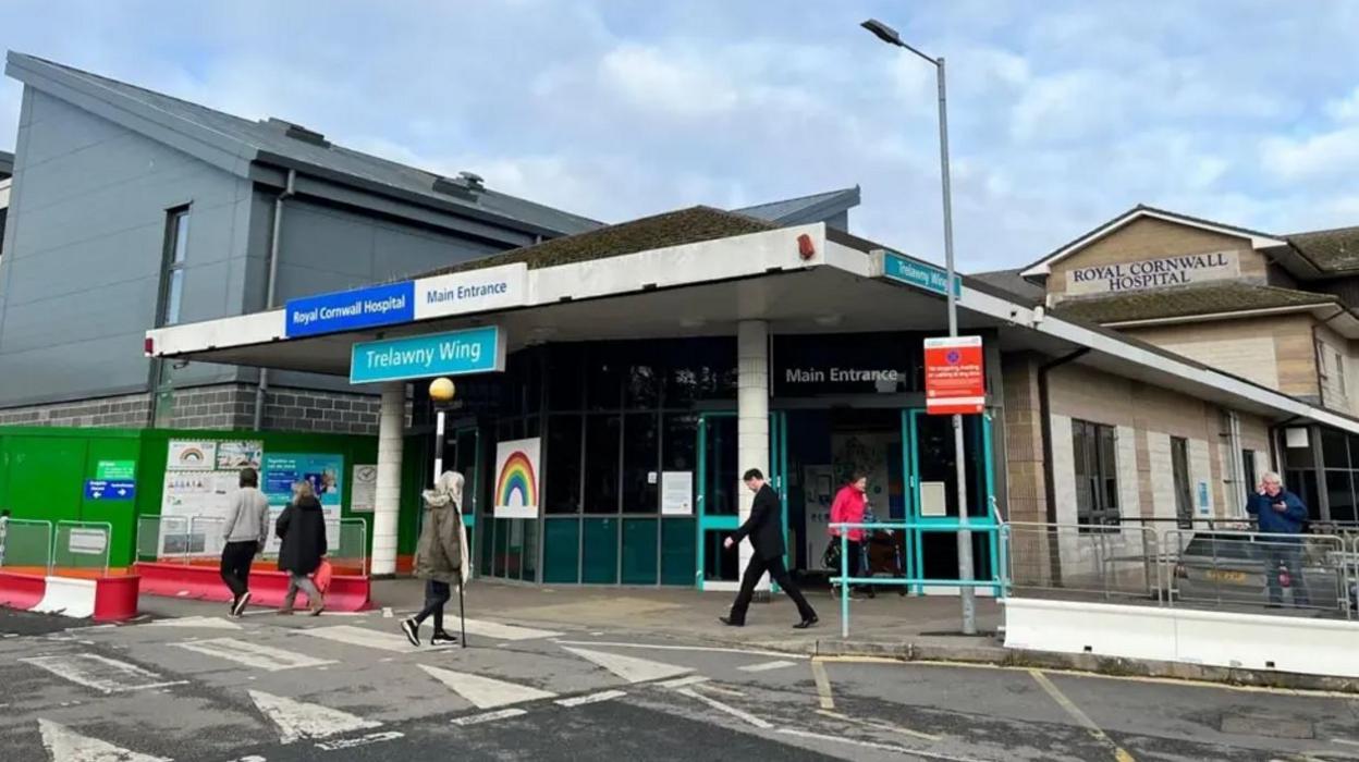 The entrance to Royal Cornwall Hospital showing people walking outside the building. 