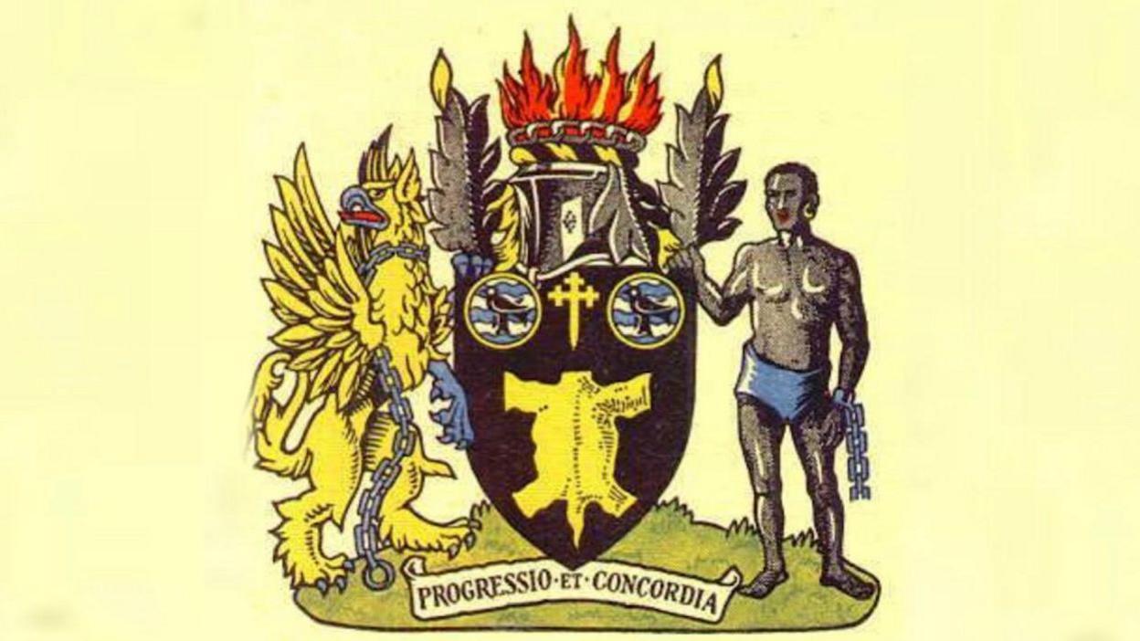 The old coat of arms showing a shield with a yellow griffin and a slave on either side