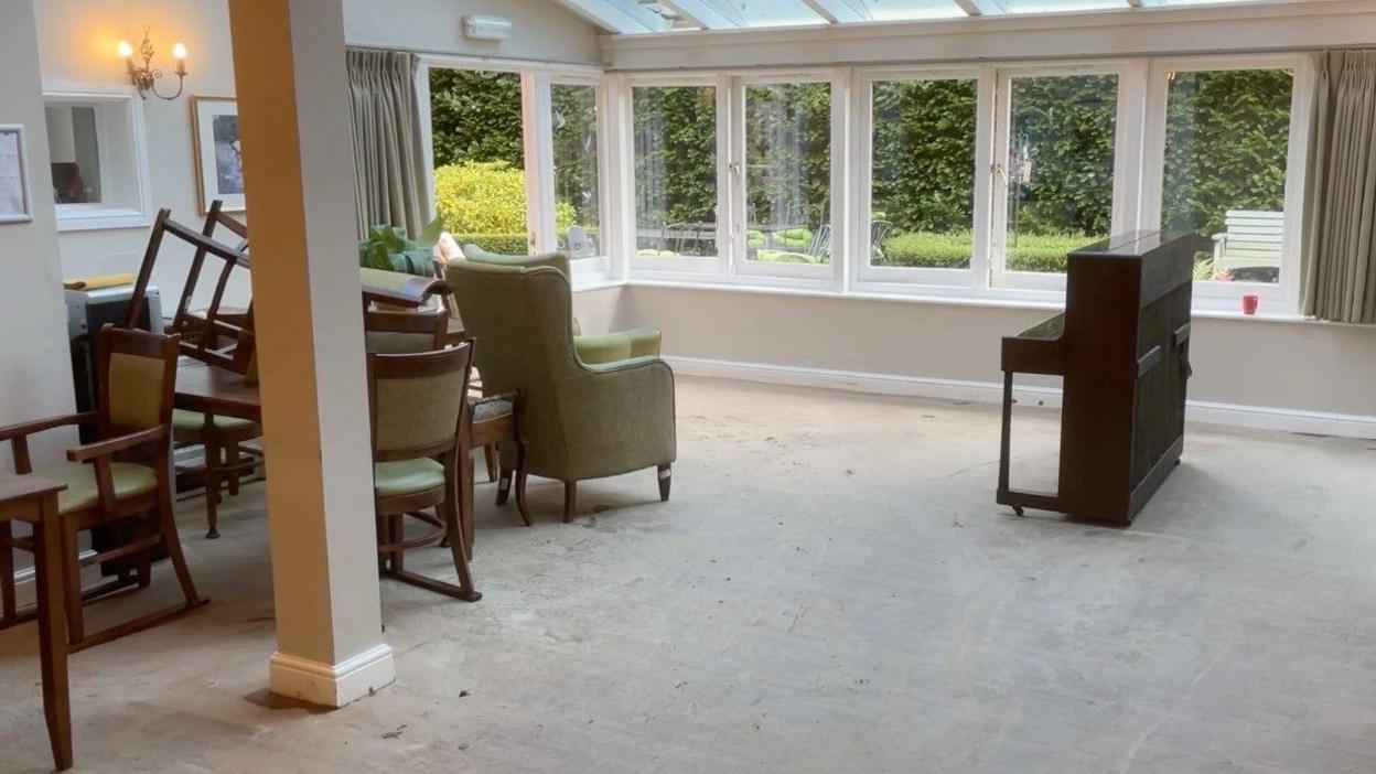 The ground floor of the care home with a piano, chairs and windows