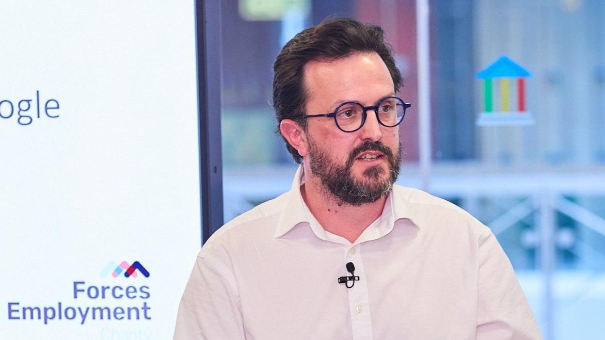 James Murphy in a white shirt addresses a conference