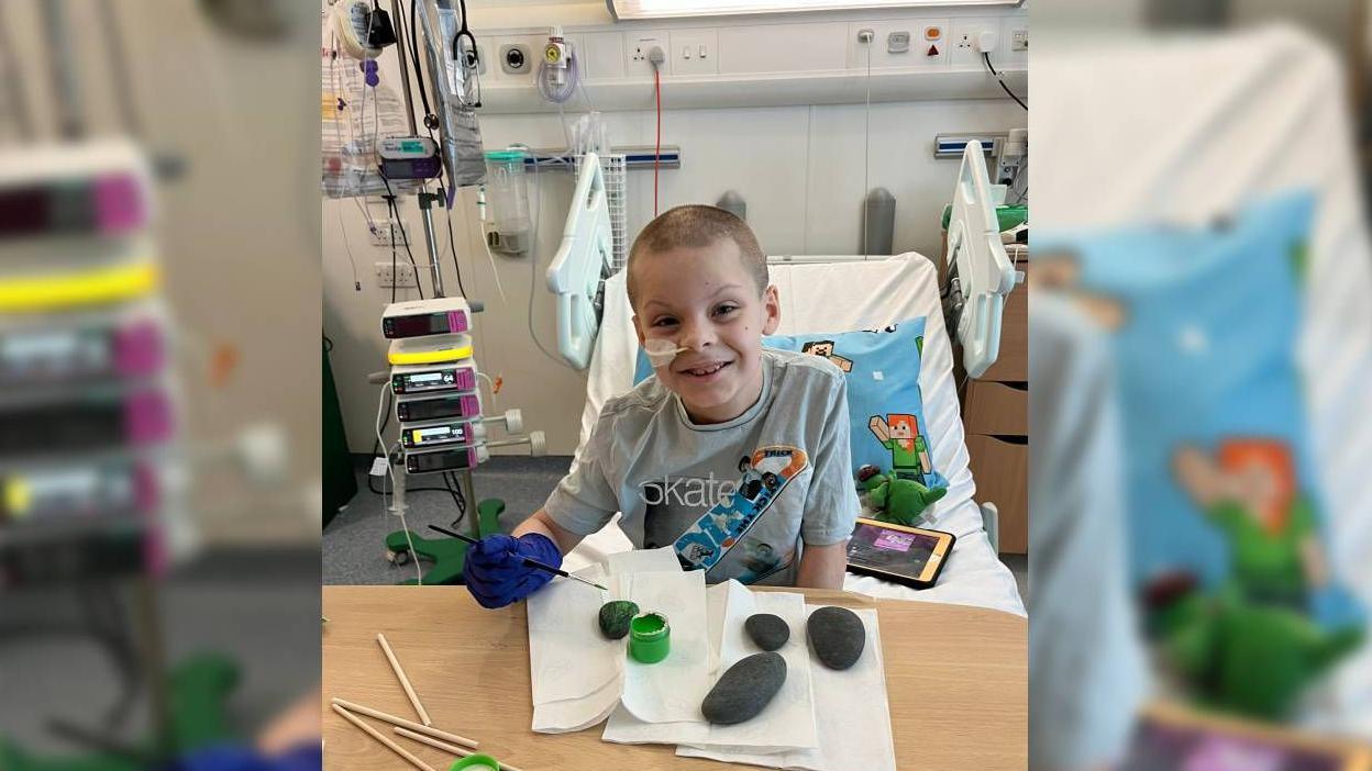 Jasper pictured painting rocks in bed in hospital 