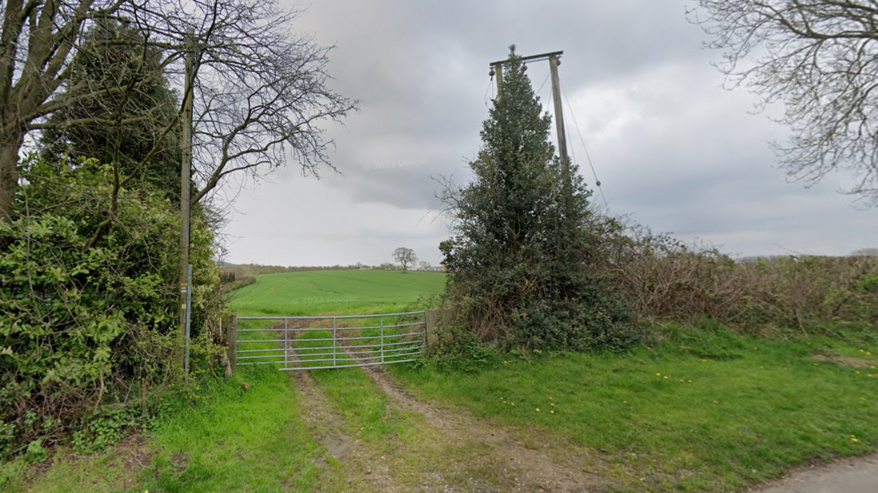 A gate into open fields viewed from a road