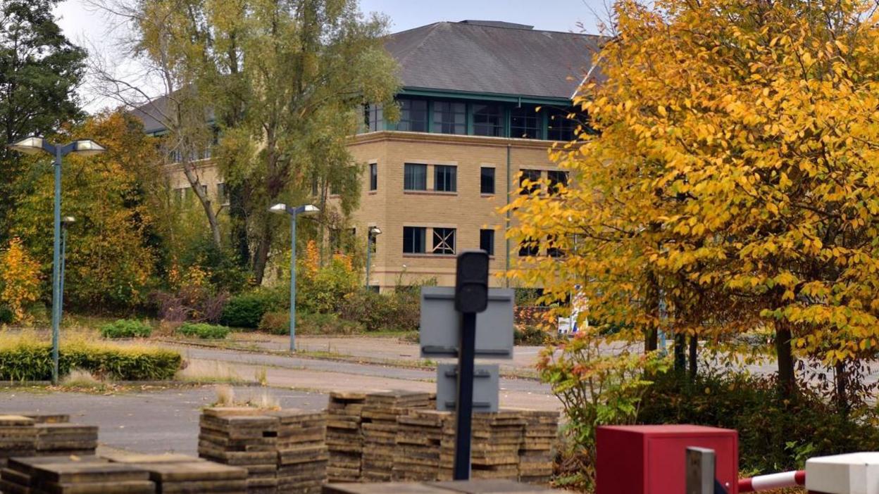 A stack of paving slabs in rows in a car park, with Aire Valley House in the background