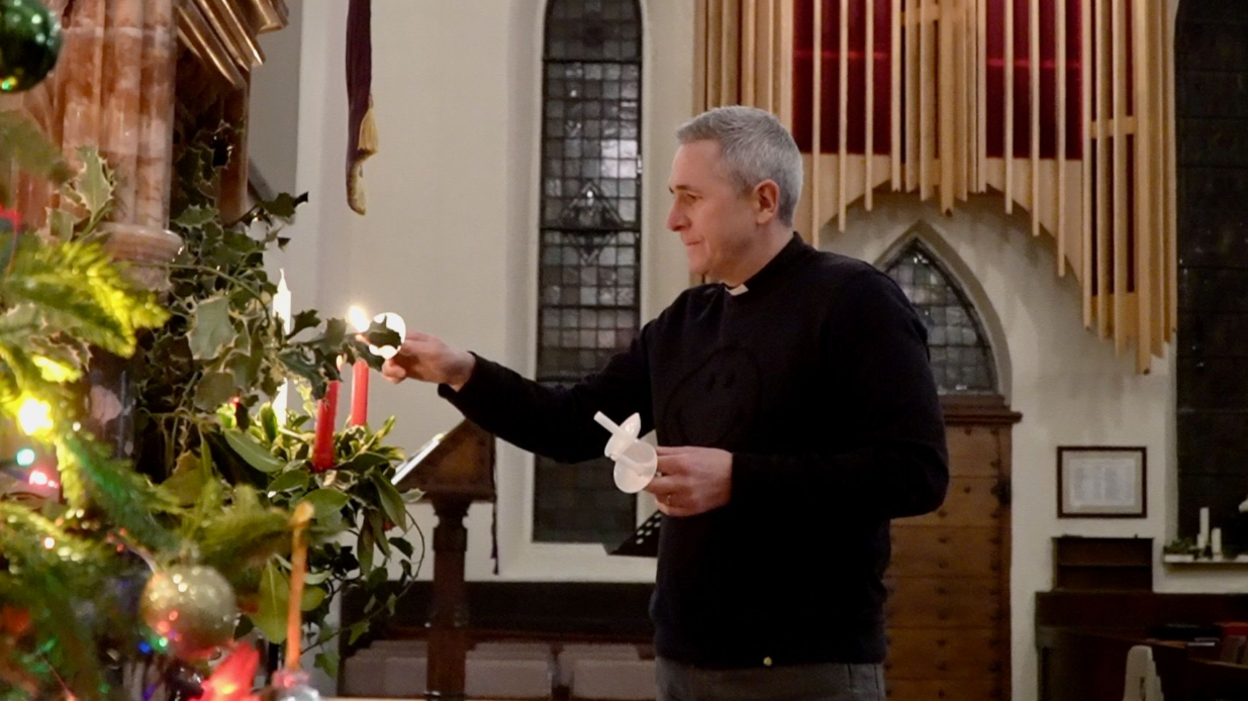 Rev Matt Woodcock, vicar at St Stephen's Church in York, lights a candle from one to another inside a church.