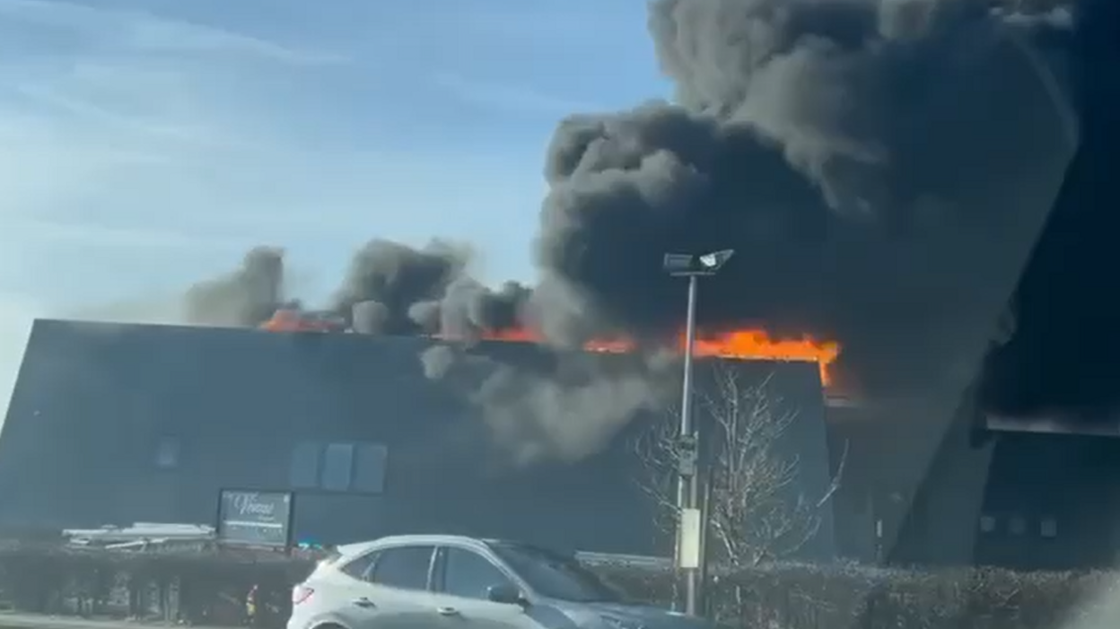 A large plume of black smoke engulfs above organge flames on the building