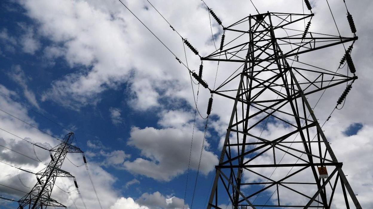 Electricity pylons against a cloudy sky