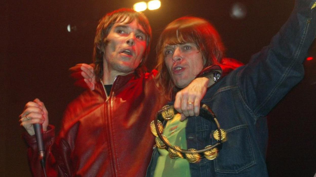 Ian Brown and Mani with their arms around each other on stage in 2004