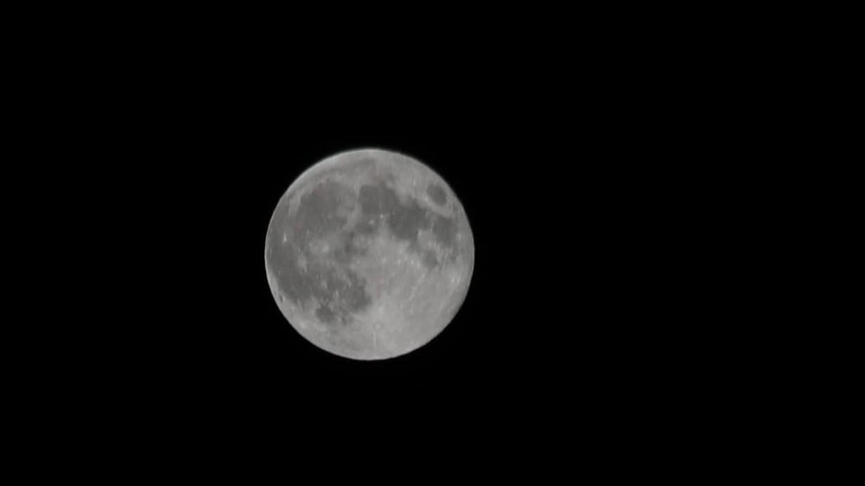 A grey moon in the middle of the image with a clear black sky surrounding it