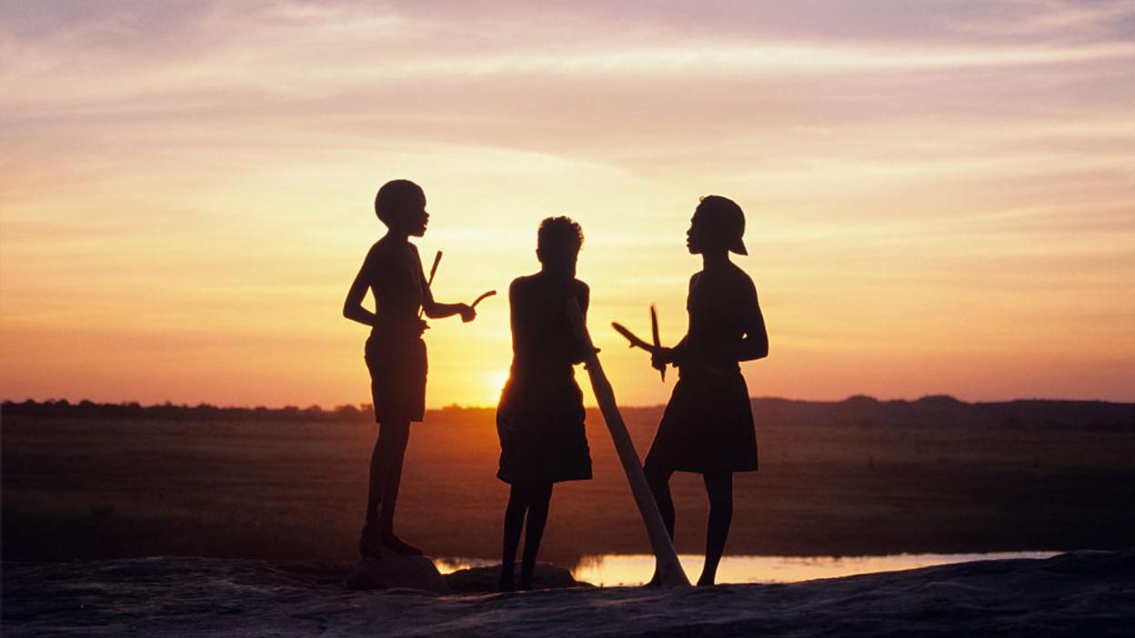 Aboriginal boys making music as the sun goes down.