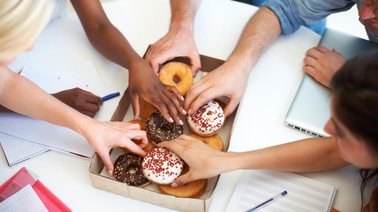 Colleagues reaching for donuts