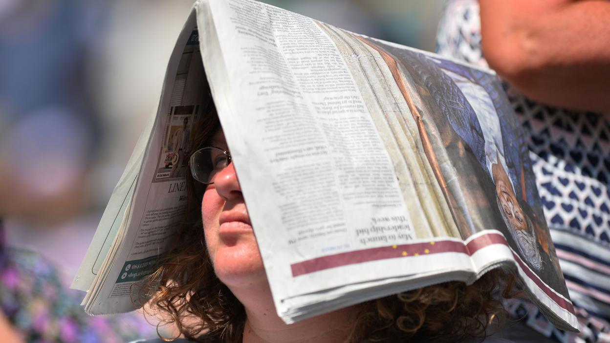 Lady at Wimbledon with newspaper on her head