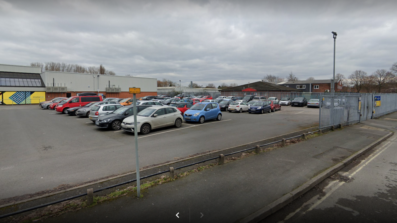 Car park full of cars behind grey metal fencing
