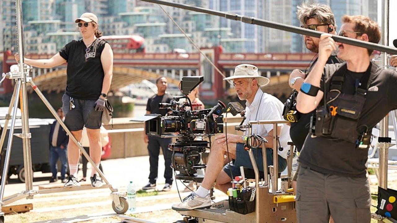 Tim Palmer sits at a camera on a film or TV set surrounded by other crew