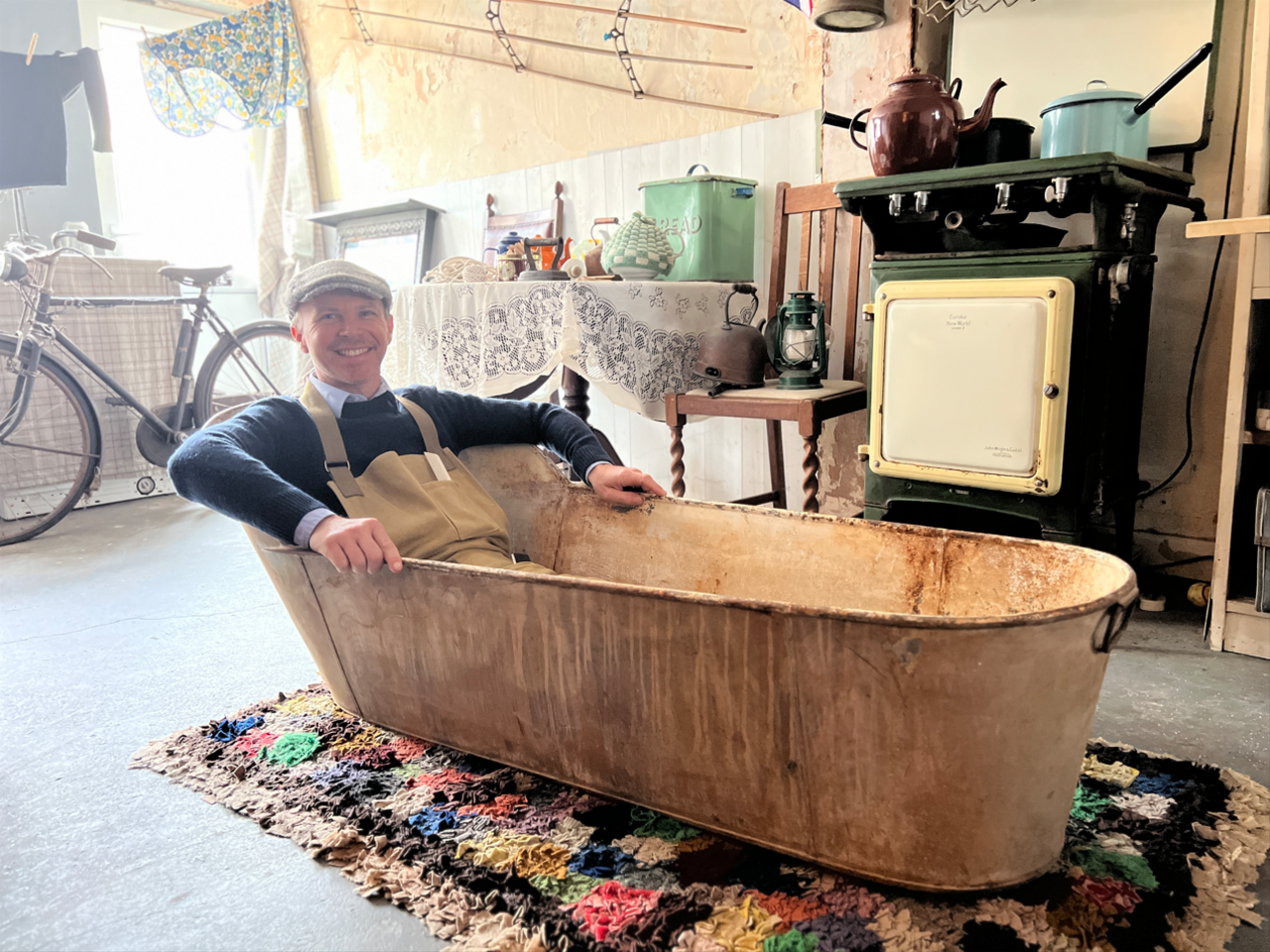 Anthony Bates sits in a tin bath in front of a fireplace in the back of his barbers shop