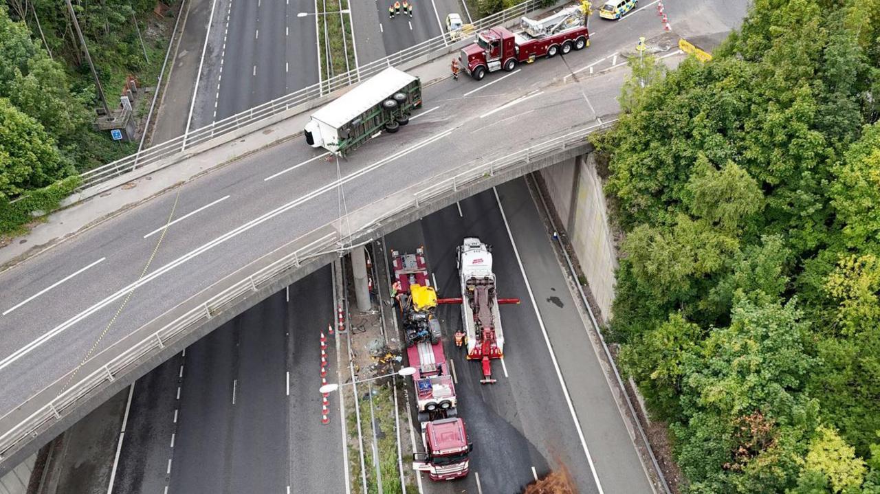 An aerial view of a tractor that fell onto the M20 motorway from the A227 overbridge, near Wrotham, shortly after 11.15 BST. Photo shows it being removed from the scene.