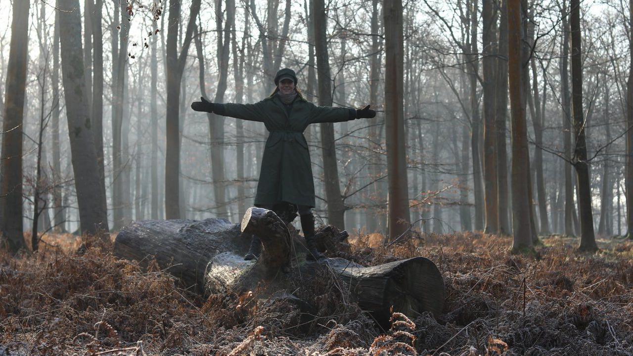 Catherine Princess of Wales, with her arms open, wearing a winter coat, in woodland in Windsor