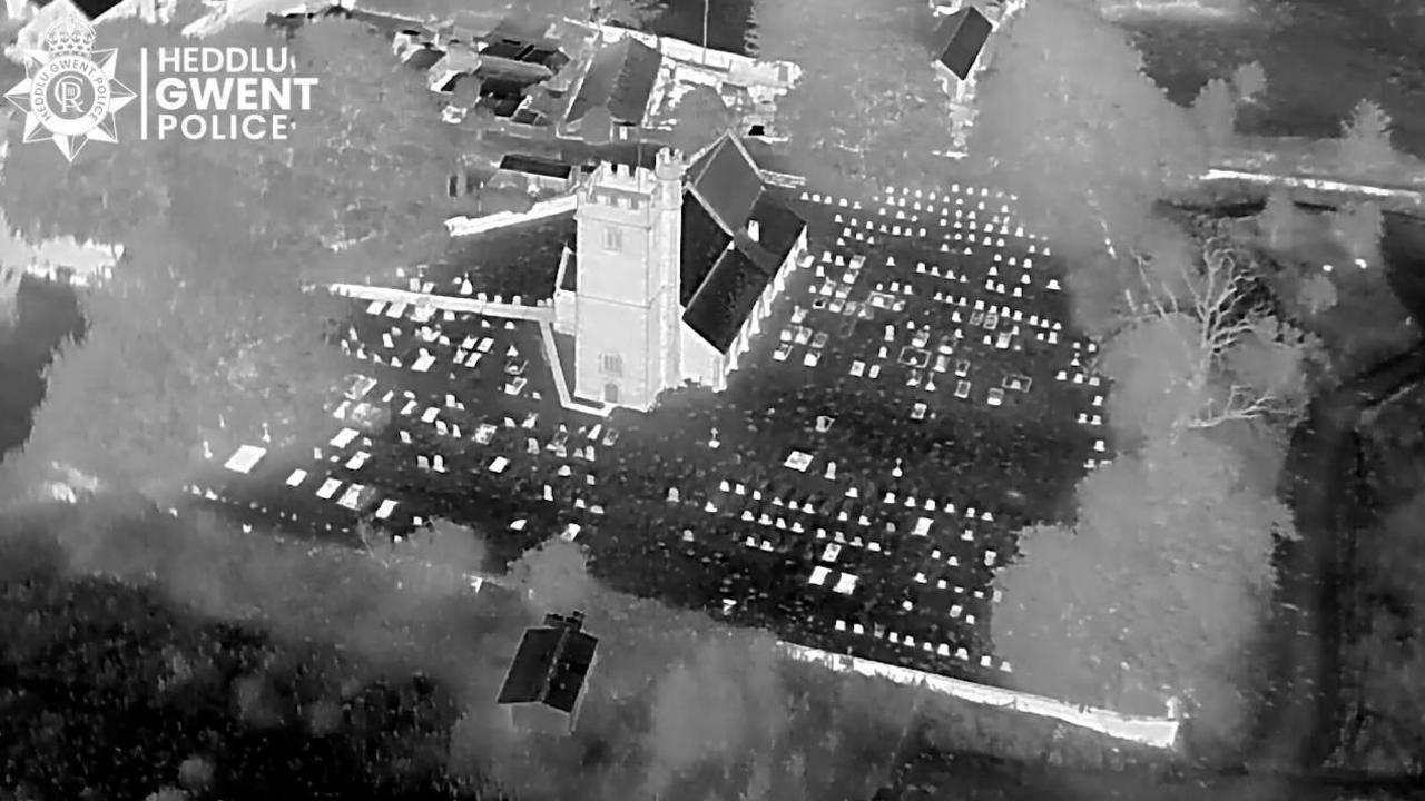Delwedd o fynwent liw nos o gamera synhwyro gwres a dron