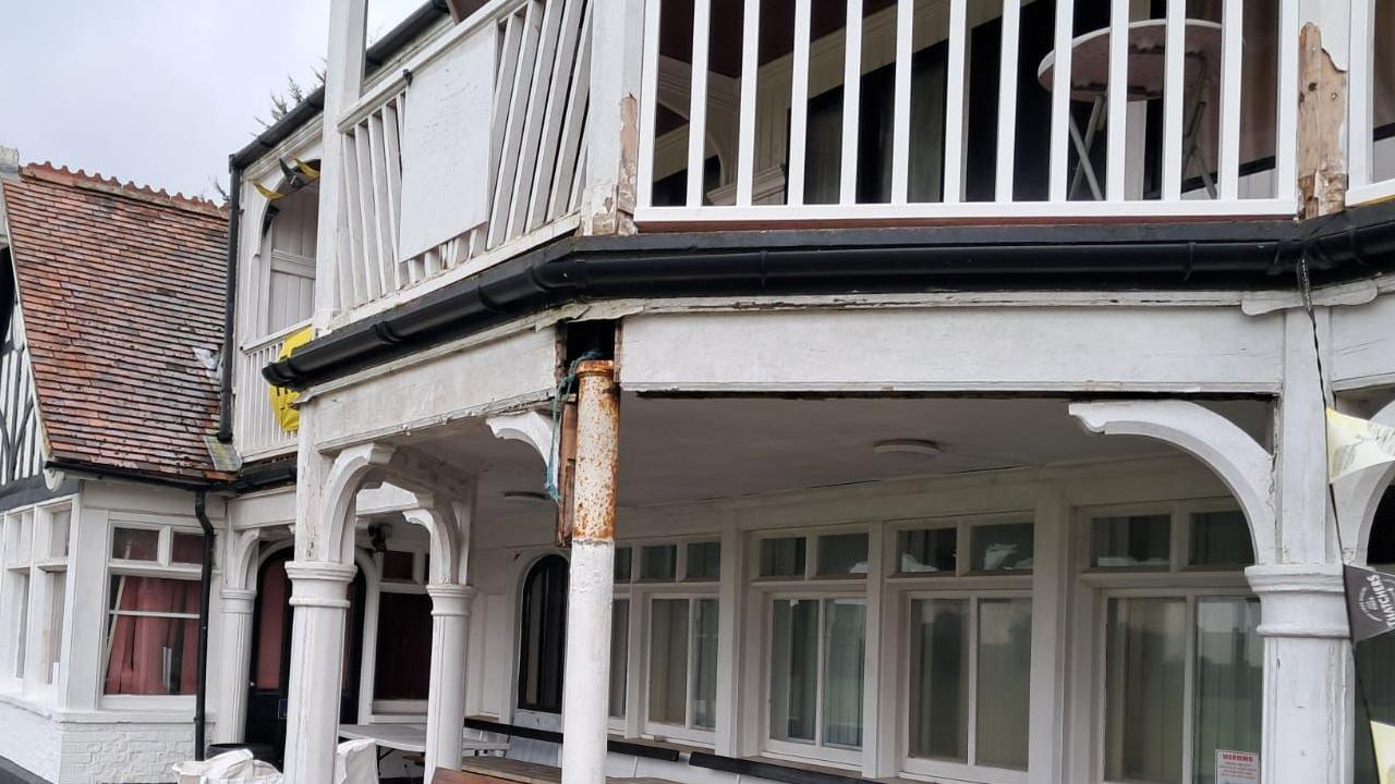 A close-up of part of the front of the pavilion building, showing areas of wood dropping off.