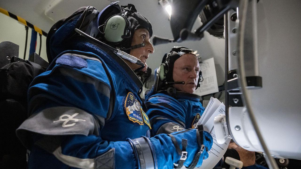 Both astronauts are in theri blue Boeing astronaut suits seated in the cockpit of the Starliner Capsule. 