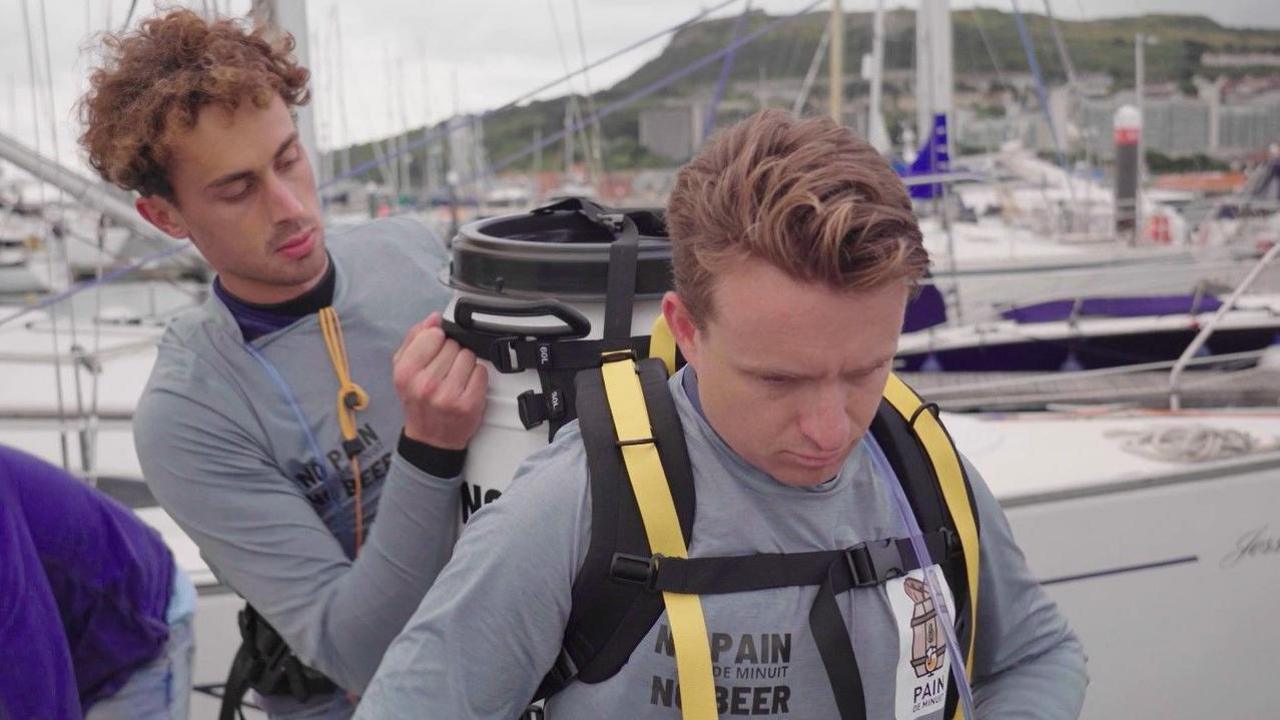 Martin Marescaux helping Theo Vanmarcke strap a white barrel to his back