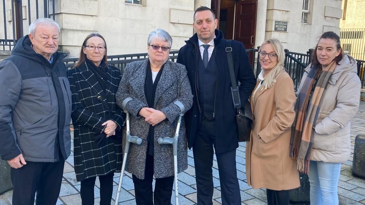 A group of five people standing in a row looking at the camera.