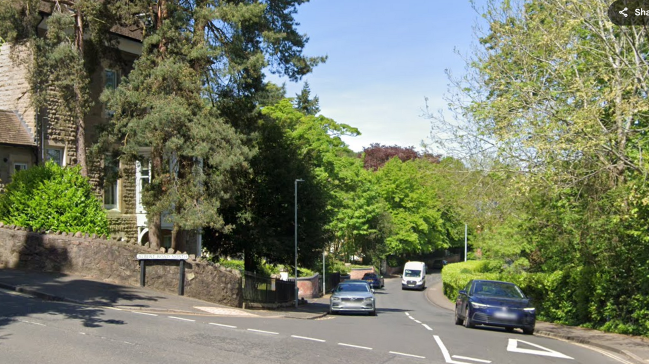 The junction of Albert Road North and Church Street in Malvern. The junction is on a hill and there is a house on the corner. The area has trees and gardens. There are parked cars on the road and two vehicles are approaching the give way line.