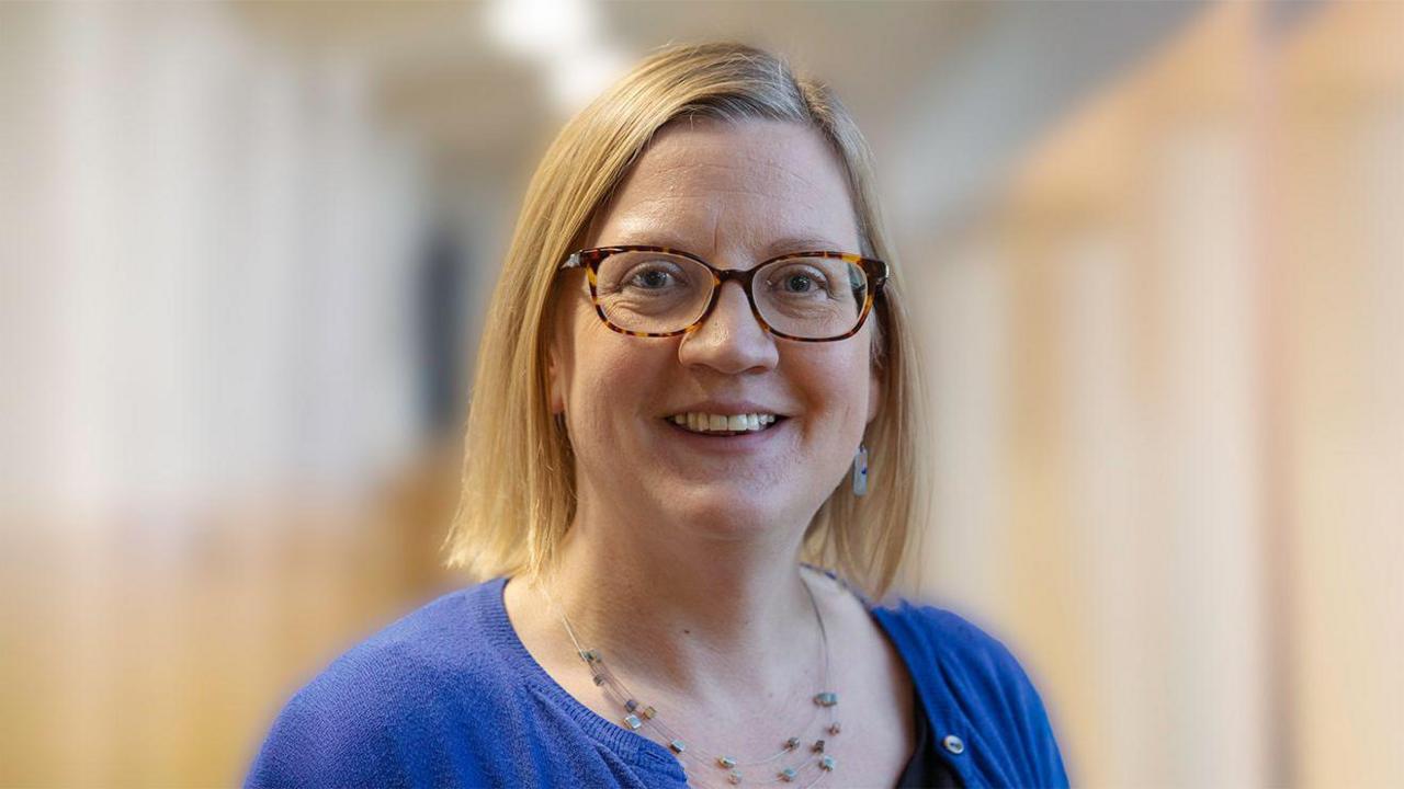 A smiling woman with blonde hair and glasses