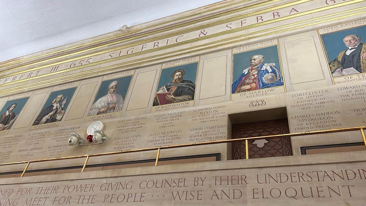 A marbled wall in Essex county hall. On it are murals of famous residents from the past including William Morris and Elizabeth Fry.