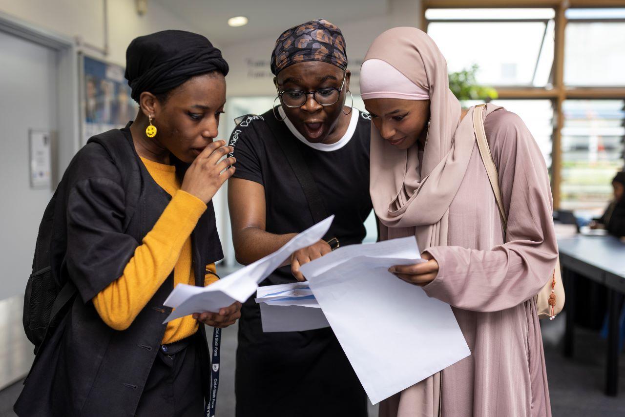 Three students look at their A-level results in shock. 