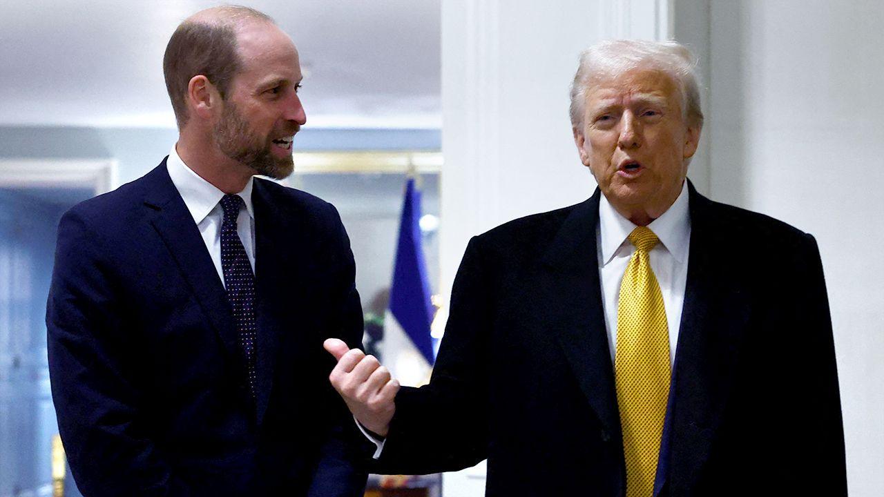 Prince William, dressed in a dark suit and tie, speaks with Donald Trump, who wears a dark suit, white shirt, and yellow tie.