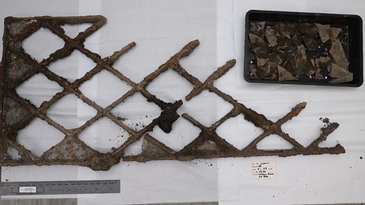 Brown-rust iron bars are held together partially in a lattice pattern. As the iron is view from left to right the iron starts to crumble more. A black box to the top right of the frame is filled with smashed small brown-iron fragments.
