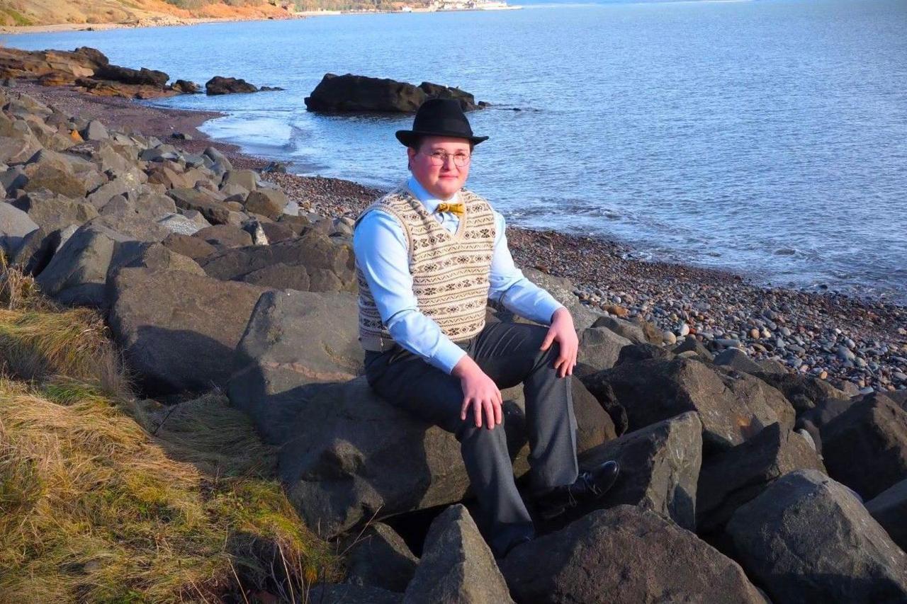 Callum sat on rocks beside the sea