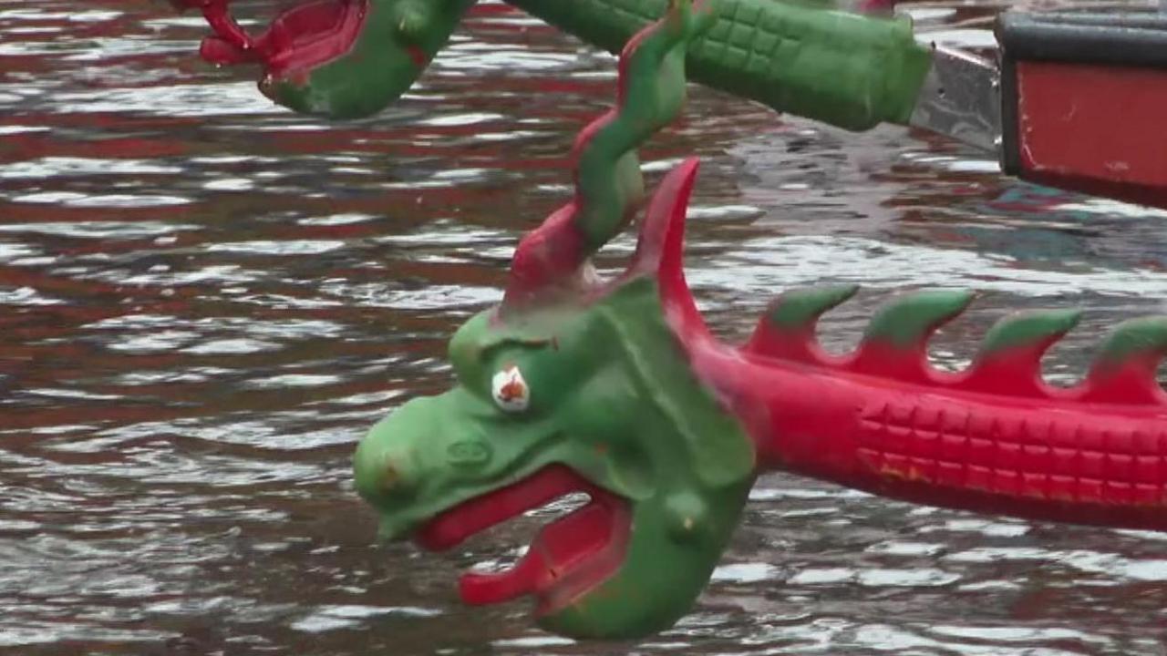 The green dragon head of boat, which has painted red lips and a white and red eye, is seen just above the water of the River Ouse