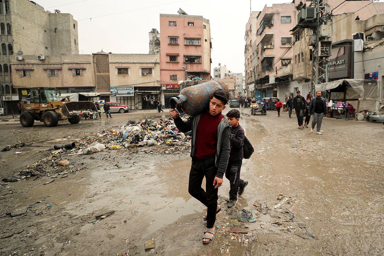 A young boy walks through a street in Gaza City on 3 February while carrying a tank of water