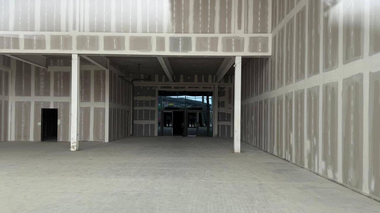 The inside of an empty unit at a leisure park. The grey-coloured floor and the walls appear to be rendered, without any decorating.